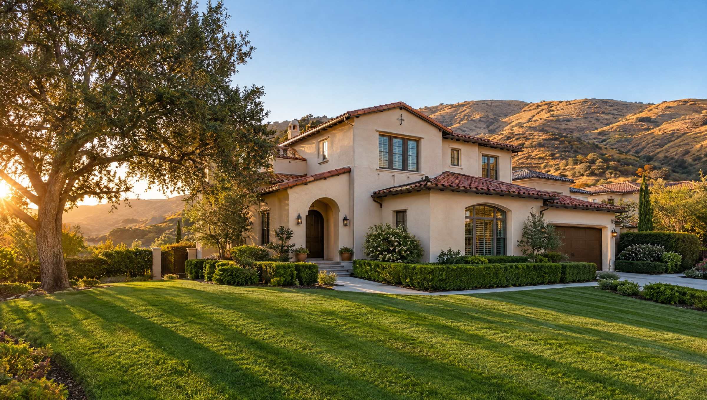 Freshly mowed, striped front lawn of a Spanish-style home in the Santa Clarita Valley at golden hour, golden hills behind